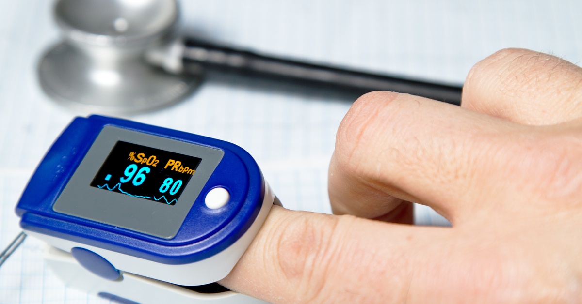 A close-up view shows a person's hand with a blue pulse oximeter on the pointer finger. A stethoscope is next to it.