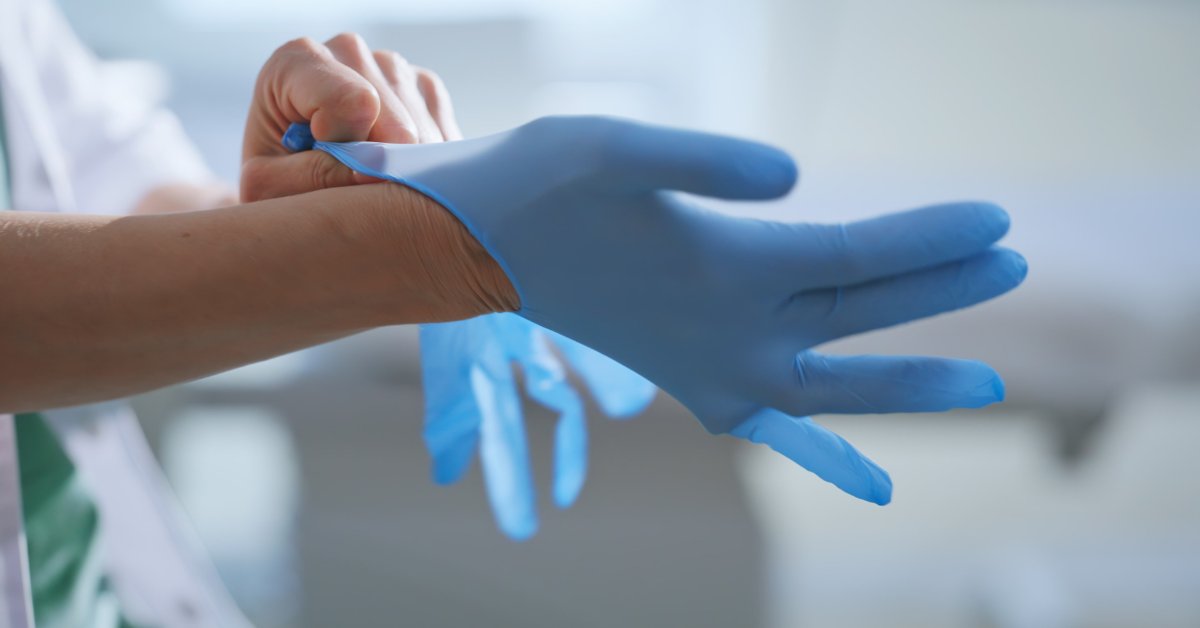 A medical professional is pressing a Doppler on the neck of a male patient and pointing to the ultrasound screen.