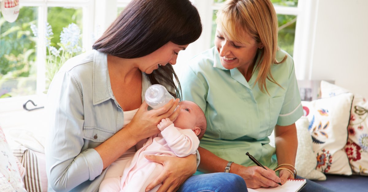 Must-Have Midwifery Supplies for Every Practice A mother is holding a newborn in her arms and feeding the baby with a bottle. A midwife is writing in a notebook.