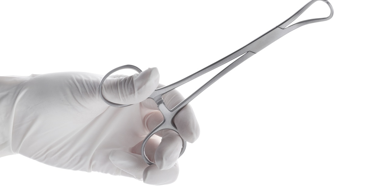 5 Medical Instruments Used During IUD Procedures A gloved hand holds stainless steel tenaculum forceps, a surgical instrument used in gynecological procedures.