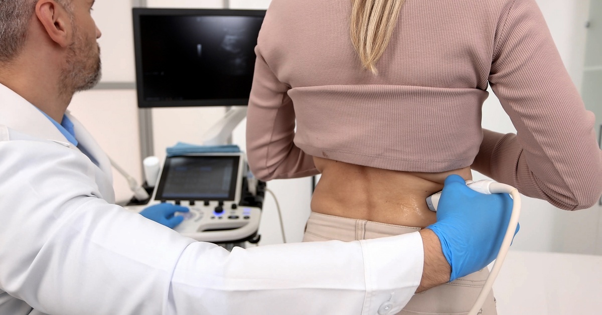 Exploring Recent Innovations in Doppler Signal Processing A physician uses a Doppler ultrasound machine to examine a patient's kidneys in a medical examination room.